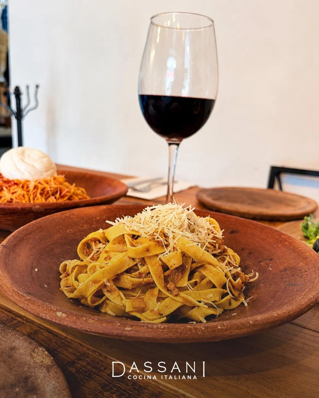 Tagliatelle, espagueti y una copa de vino sobre la mesa de Dassani